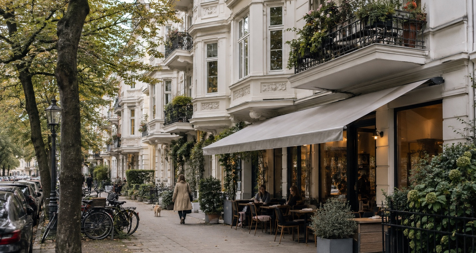 Straße mit Altbauten, Bäumen und Cafés